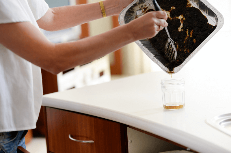 Person in kitchen scraping food scraps from tray