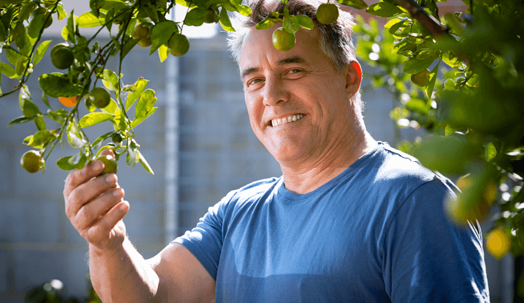 Man smiling holding onto a tree branch