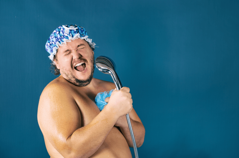 Man singing into a showerhead while having a shower