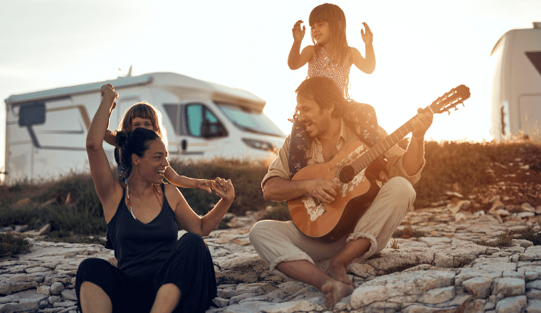 Young family at a holiday stop playing guitar